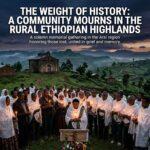 An editorial, cinematic news illustration depicting a solemn memorial gathering in the rural Ethiopian highlands of the Arsi region at dusk. In the foreground, rural Ethiopian community members of East African descent, draped in traditional textured white woven cotton Netela and Gabi shawls, stand together in quiet grief and solidarity, holding softly glowing beeswax candles that cast a warm, flickering light across their solemn, dignified faces. In the midground, the timeless architecture of a rural Ethiopian Orthodox stone chapel stands perched against the rolling green and earthy contours of the misty highland hills. The atmosphere is poignant, reverent, and heavy with historical weight, rendered in rich twilight tones of deep indigo, slate, and warm candlelit amber with documentary photography depth. Positioned across the upper third of the composition is a bold, high-impact text overlay reading 'FAITH & FRACTURE: ARSI ZONE' in a modern, ultra-clean sans-serif typeface, styled in brilliant cream-white lettering with a subtle warm gold underline and a deep charcoal drop shadow for maximum legibility and sharp contrast against the darkening twilight sky.